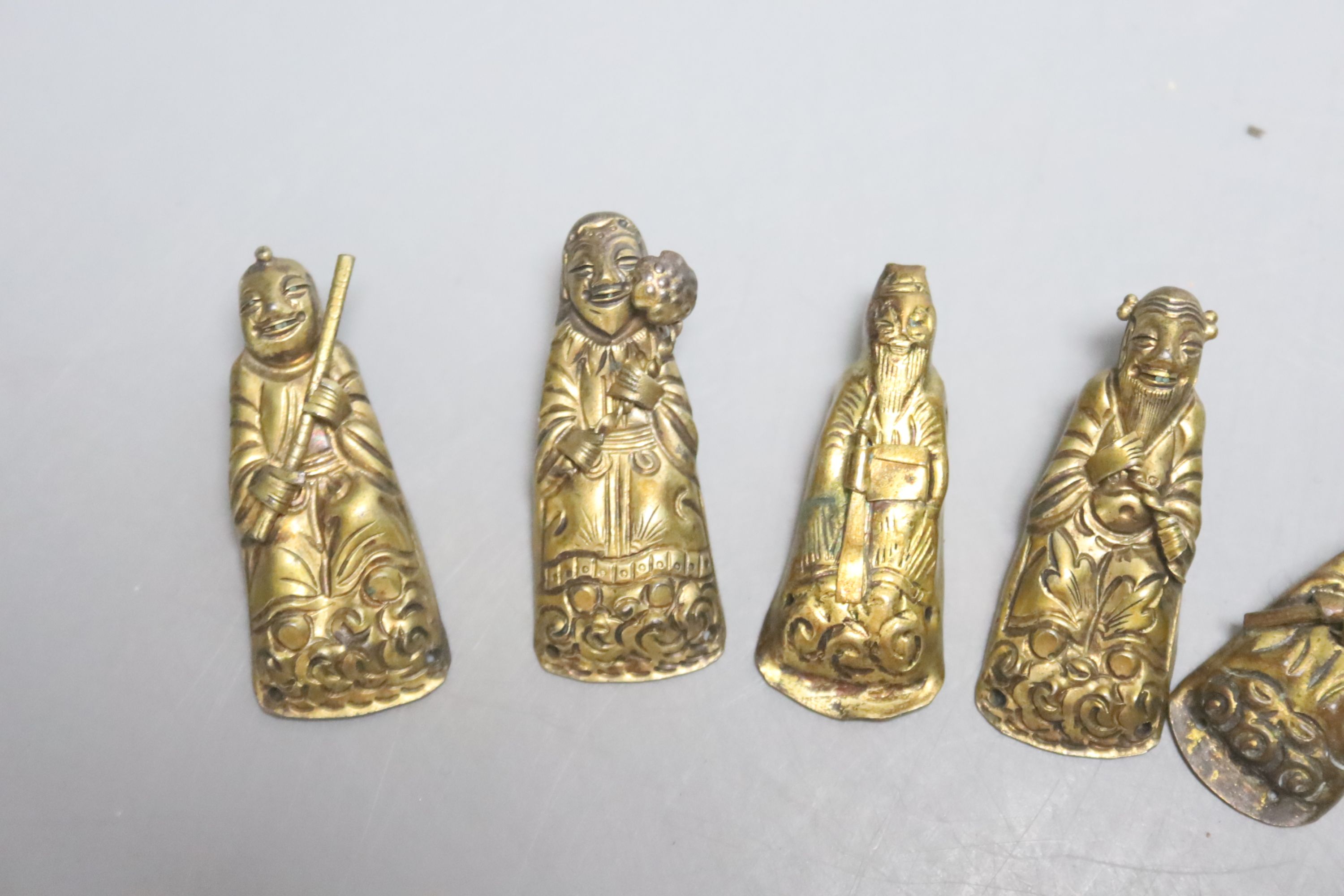 A group of eight Chinese figural pressed metal figural mounts in the form of sages, each 3.5cm. long.